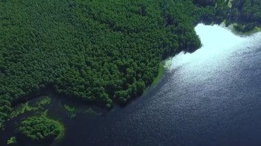 Gökyüzünün göl yansıması ve yeşilliklerle kaplı kıyı.
