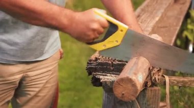 Bir adamın eli testereyi tutar ve tahtaları keser.