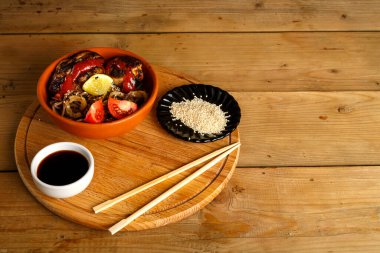 Yuvarlak bir büfede tavuklu soya sosu ve çubukların yanında susam tohumlu soba..