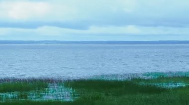 Rüzgardan gelen dalgalar ve gökyüzünde akan beyaz zaman bulutları.