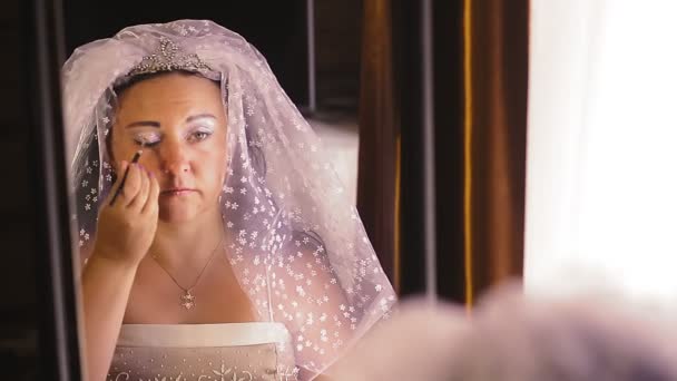 Uma noiva judia na frente de um espelho para o casamento está fazendo maquiagem. — Vídeo de Stock