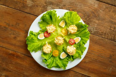 Peynirli tart ve sarımsak tabakta bıldırcın yumurtası salatası ve ahşap masa manzarası..