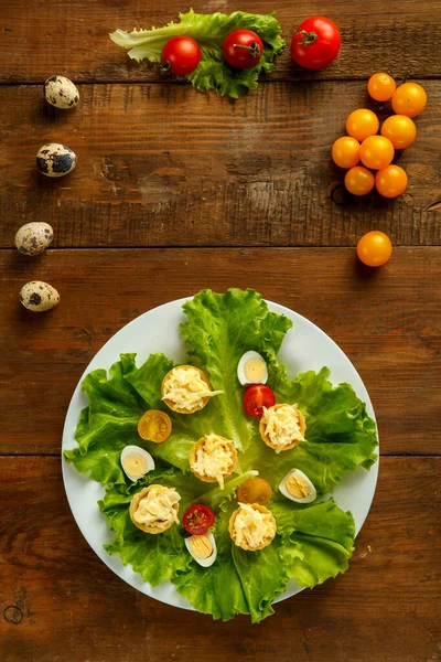 Tartlets met kaas en knoflook op een bord met kersensalade en kwarteleitjes op een houten tafel. — Stockfoto