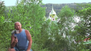 Seyahat hakkında cep telefonu olan bir erkek blogcu dağdan görünen tapınaktan bahsediyor.