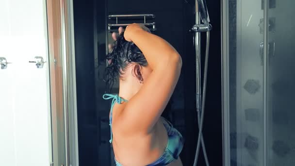 Μια γυναίκα με μαγιό πλένει το κεφάλι της στο ντους.. — Αρχείο Βίντεο