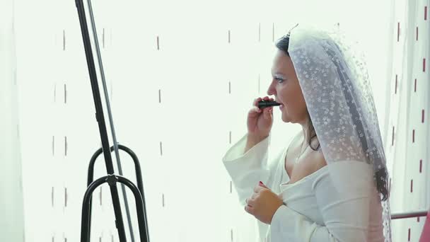 En judisk brud i klänning och slöja framför spegeln sminkar sig före hupa-ceremonin, som speglas i spegeln — Stockvideo