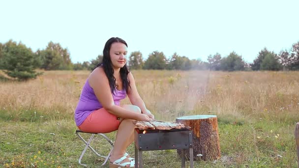 Egy nő a tisztáson grillezik, hússal a grillen.. — Stock videók