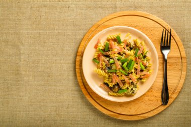 Masanın üzerinde çatal ve krema soslu jambonlu ve mantarlı bir tabak..