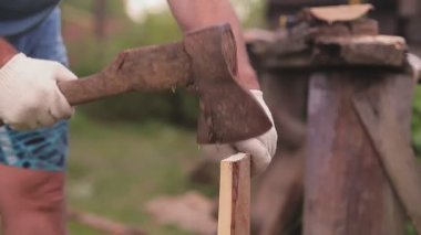 Bahçede yüzü olmayan bir adam baltayla tahtaları ayırır.