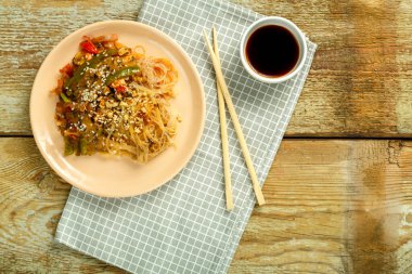 Çubuk ve soya sosunun yanındaki peçetenin üzerinde sebze ve mantarlı Funchoza..