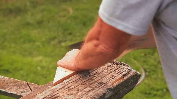 Egy férfi fogja a fűrészt és vágja a deszkákat.. — Stock videók