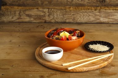 Yuvarlak bir büfede tavuklu soya sosu ve çubukların yanında susam tohumlu soba.