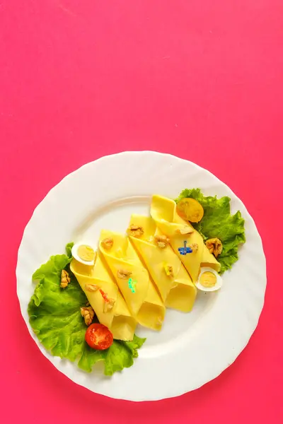 Rouleaux au fromage et à l'ail sur une assiette avec salade verte sur fond rose. sauver une place. — Photo