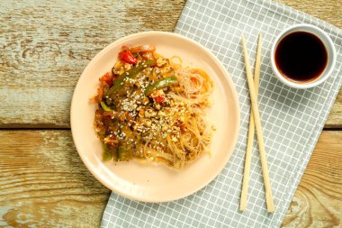 Çubuk ve soya sosunun yanındaki peçetenin üzerinde sebze ve mantarlı Funchoza..