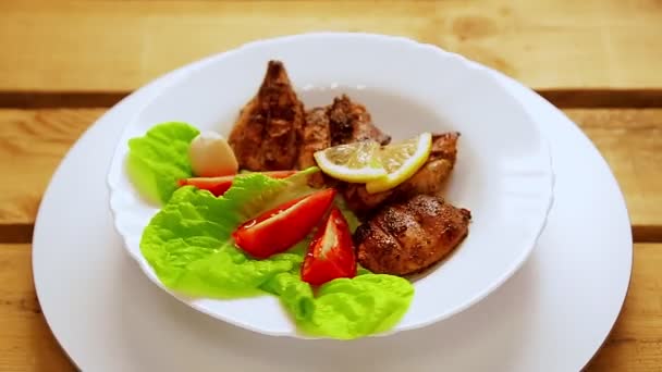 Biała płyta z kawałkami grillowanego mięsa z sałatką i cytryną obraca się w kółko — Wideo stockowe