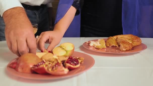 Rosh Hashana 'nın şenlik masasının yanında yüzü olmayan bir Yahudi aile bala elma bandırıyor. — Stok video