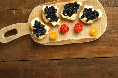 Tahta bir masanın üzerinde siyah havyarlı sandviçler, fotokopici..