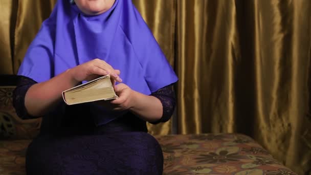 一个年轻的穆斯林女人，头戴蓝色头巾，没有脸，正在家里读那本圣书 — 图库视频影像
