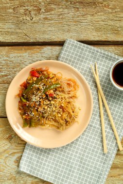 Peçetede soya sosu ve soya sosunun yanında sebze ve mantarlı Funchoza..