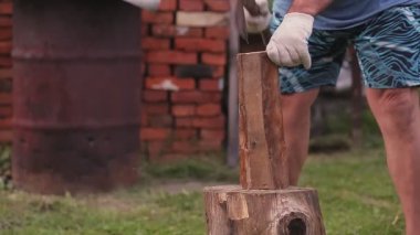 Bahçede yüzü olmayan bir adam baltayla tahtaları ayırır.