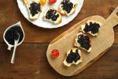 Tahta bir masada, havyar tabağının yanında siyah havyarlı sandviçler..