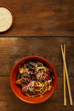 Tay soslu sebzeler ve mantarlar çubukların yanındaki kil tabakta..