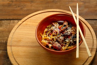 Tay soslu sebze ve mantarlı Udon ahşap bir büfede, yemek çubuklarının yanında..