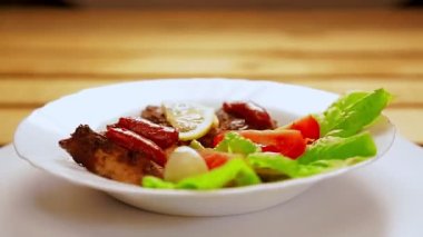 Ketçaplı, limonlu ve kirazlı, marul yapraklarında ızgara yapılmış beyaz bir tabak daire şeklinde dönüyor..