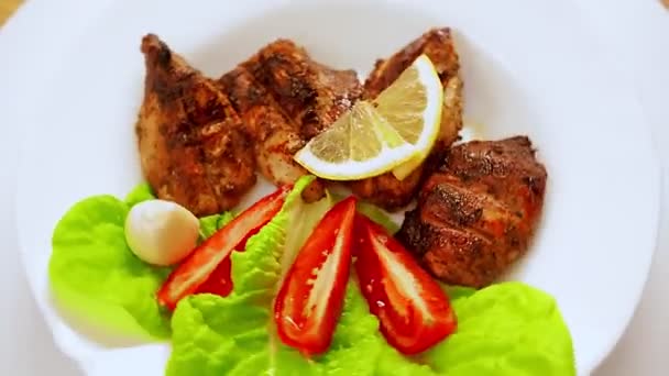 Placa blanca con trozos de carne a la parrilla en hojas de lechuga rotan en un círculo vista superior — Vídeos de Stock