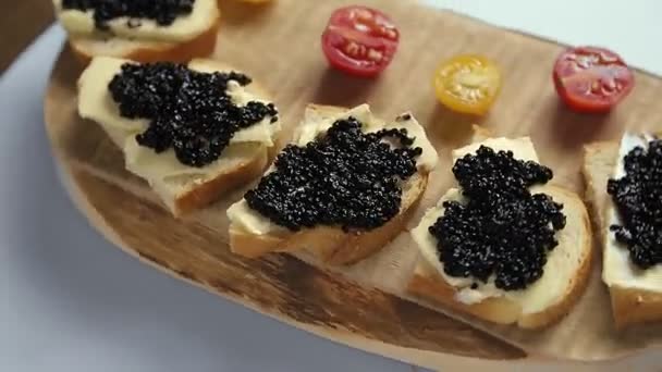 Sandwichs au caviar noir sur une vieille planche de bois tournent en cercle — Video