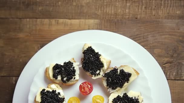 Los bocadillos con el caviar negro en el plato blanco rotan en el círculo — Vídeos de Stock