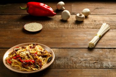 Tay soslu sebze ve mantarlı Udon, malzemelerin yanında bej bir tabakta..