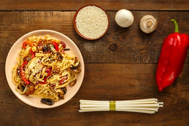 Tayland soslu tavuk ve mantarlı Udon susam ve udonun yanında bej bir tabakta..