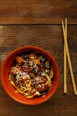 Tay soslu sebzeler ve mantarlar çubukların yanındaki kil tabakta..