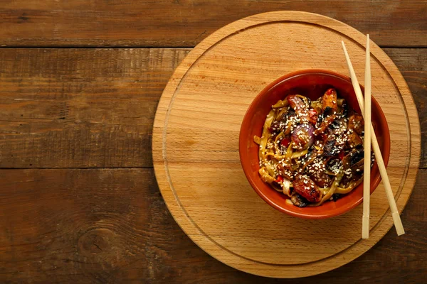 Tay soslu sebze ve mantarlı Udon ahşap bir büfede, yemek çubuklarının yanında..