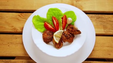 Salata ve limonla ızgara et içeren beyaz bir tabak daire şeklinde döner..