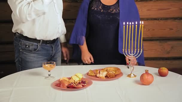 Joodse familie man en vrouw zonder gezichten naast de feestelijke tafel van Rosh Hashanah vrouw die wijn drinkt voor Kiddush — Stockvideo