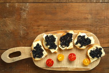 Tahta bir masanın üzerinde siyah havyarlı sandviçler, fotokopici..