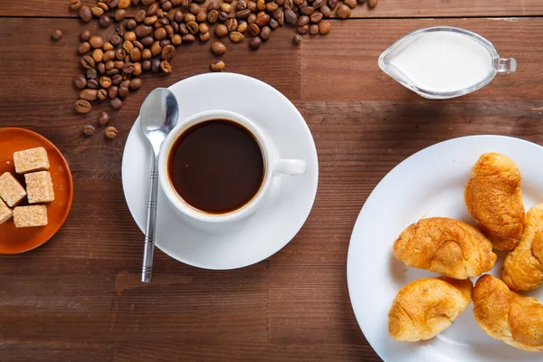 Чашка кофе на столе рядом с сахаром и сливки в кувшине и круассан. — стоковое фото
