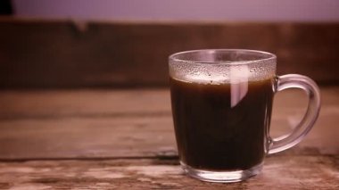 Bir kadının eli bir fincan kahveye esmer şeker atar ve kaşıkla karıştırır..