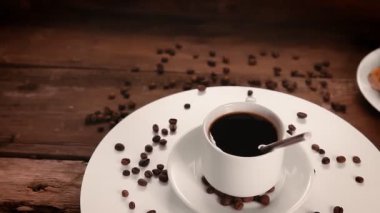 Bir fincan kahveyi kaşıkla tepside dağılmış kahve çekirdekleri daire şeklinde döner.