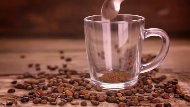 O café é derramado em uma caneca em pé entre uma dispersão de grãos de café e água é derramada — Vídeo de Stock