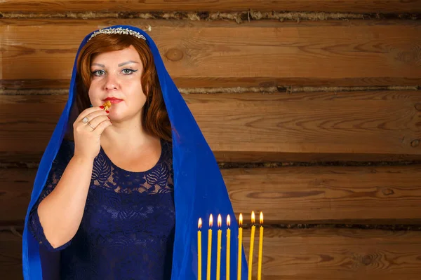 在Rosh Hashan前夕，一位犹太妇女站在燃烧着的蜡烛旁边，手里拿着一片蜂蜜苹果. — 图库照片