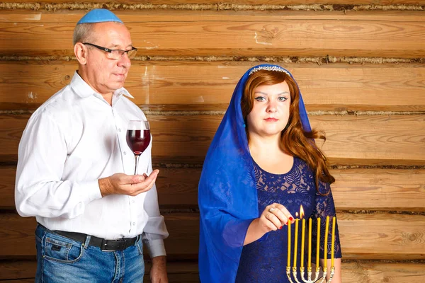 在Rosh Hashanah前夕，犹太家庭的丈夫和妻子坐在餐桌前，一个男人为Kiddush的女人把酒点着蜡烛. — 图库照片