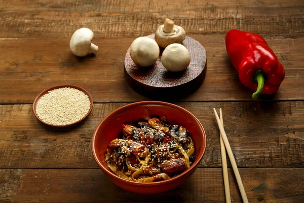 Udon con verdure e funghi in salsa thai pad in un piatto di argilla con le bacchette ingredienti nelle vicinanze. — Foto Stock