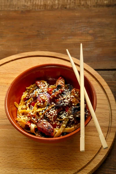 在筷子旁边的木制圆盘上，放着蔬菜和蘑菇在沙司酱里的便盆里. — 图库照片