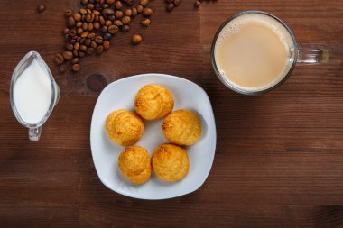 Sütlü kahve, bir sürahi krema ve ayçöreği olan bir kupa kahve çekirdekleri arasında masanın üzerinde. Yatay fotoğraf