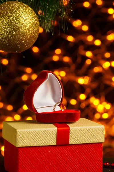 Altın çelenk Noel ağacı dalından Bokeh Noel ağacı hediyeleri ve mum altında parlak bir top. Dikey fotoğraf.