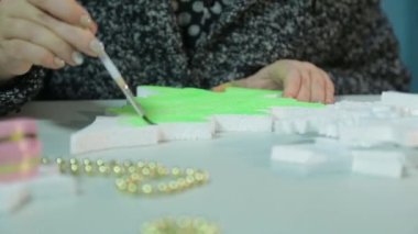 Kış akşamları kadınların elleri, Noel için yeşil suluboyalı bir Noel ağacı heykelciği yaparak ev dekorasyonu yapar..