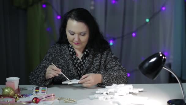 Een jonge vrouw maakt thuis decoraties voor Kerstmis door het schilderen van sterren met verf. — Stockvideo